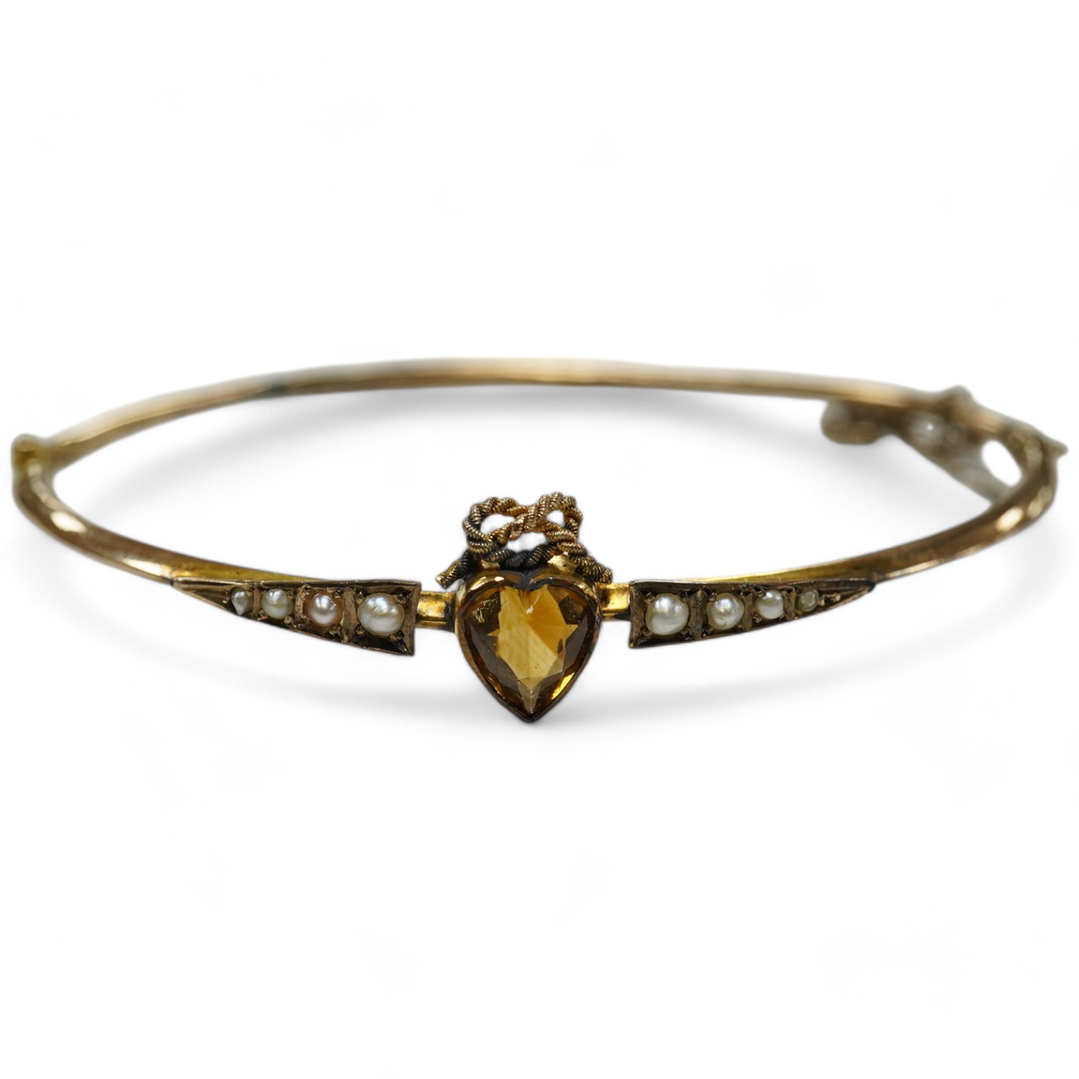 A Victorian yellow metal, citrine and seed pearl set hinged bangle, with heart shaped citrine, interior diameter 62mm, gross weight 4.6 grams, with fitted leather box. Condition - poor